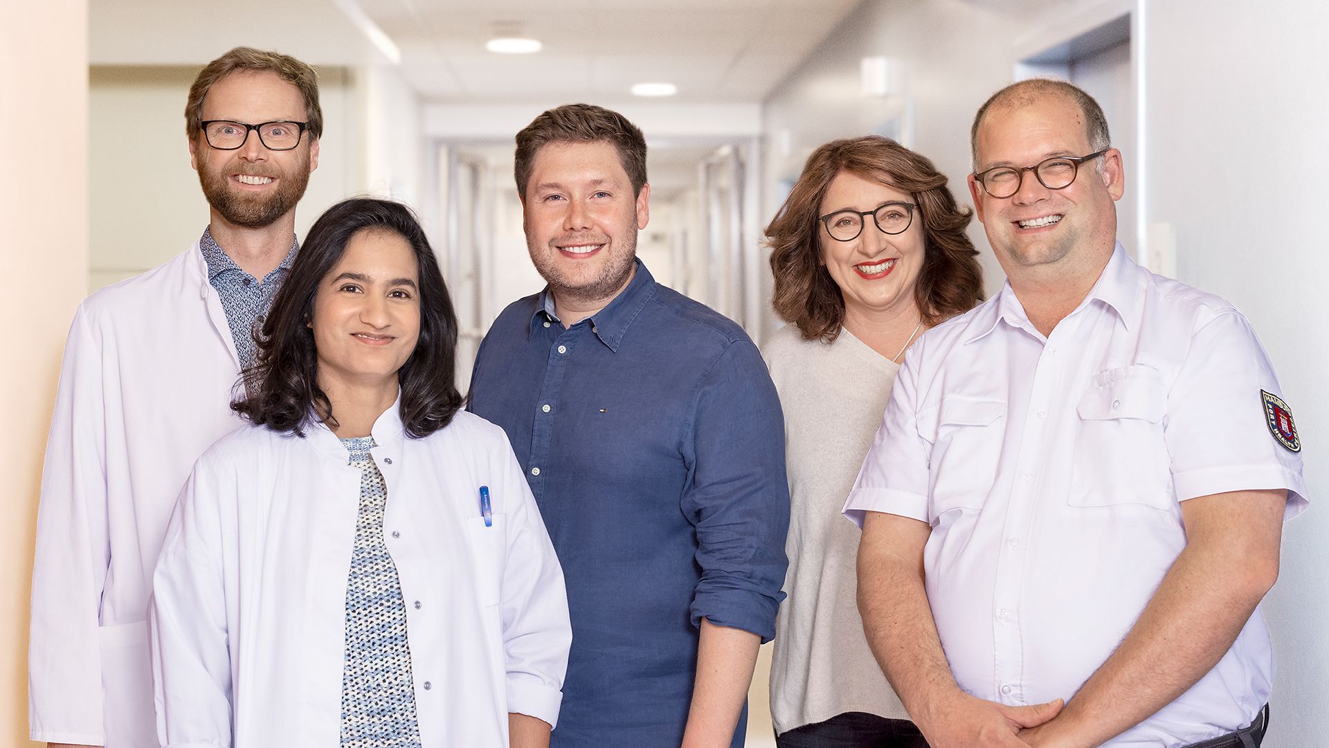 Fünf Ärztinnen und Ärzte lächeln in die Kamera