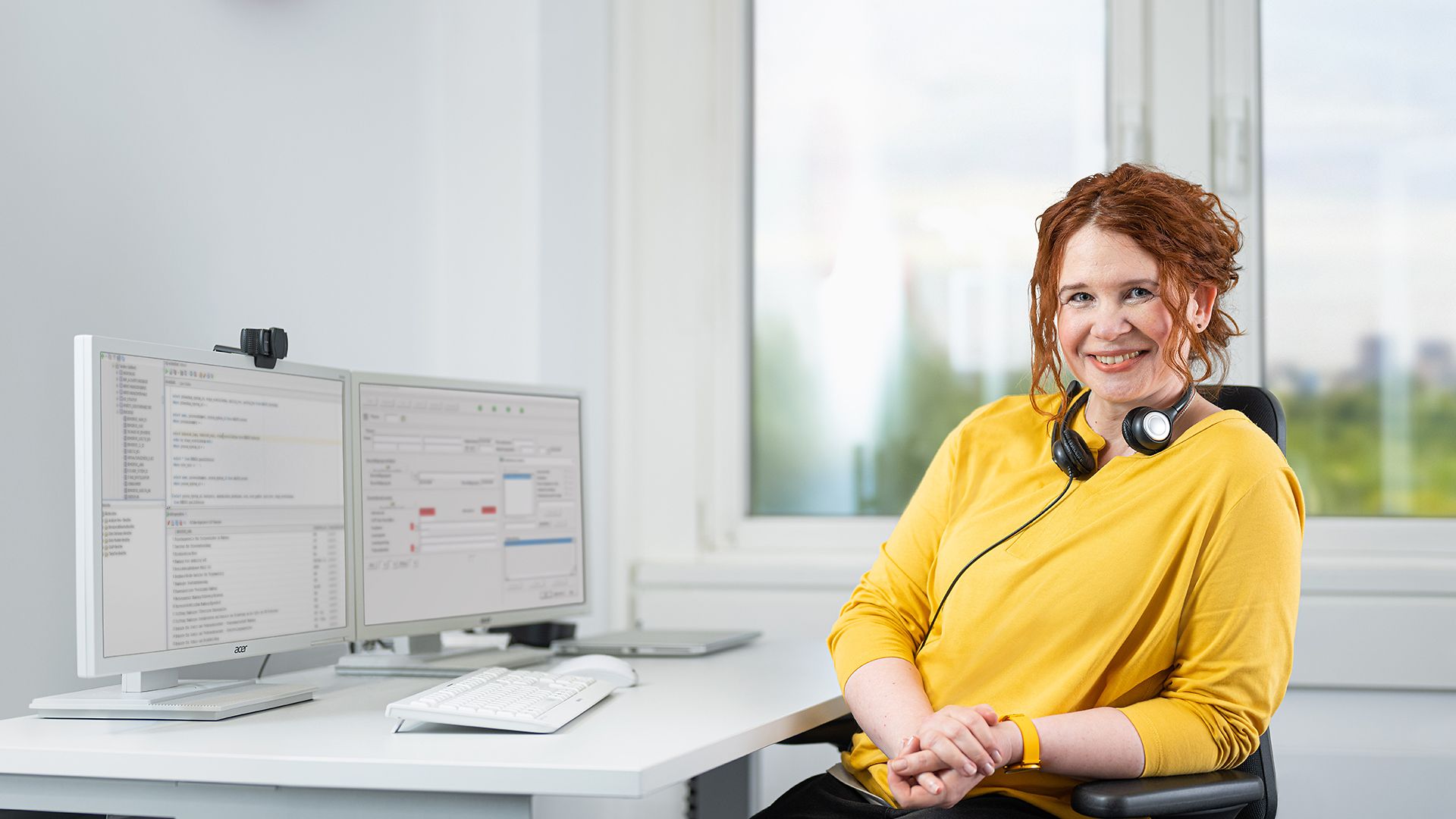 Eine Mitarbeiterin aus dem Bereich Operative IT sitzt mit einem Headset vor ihrem Computer.