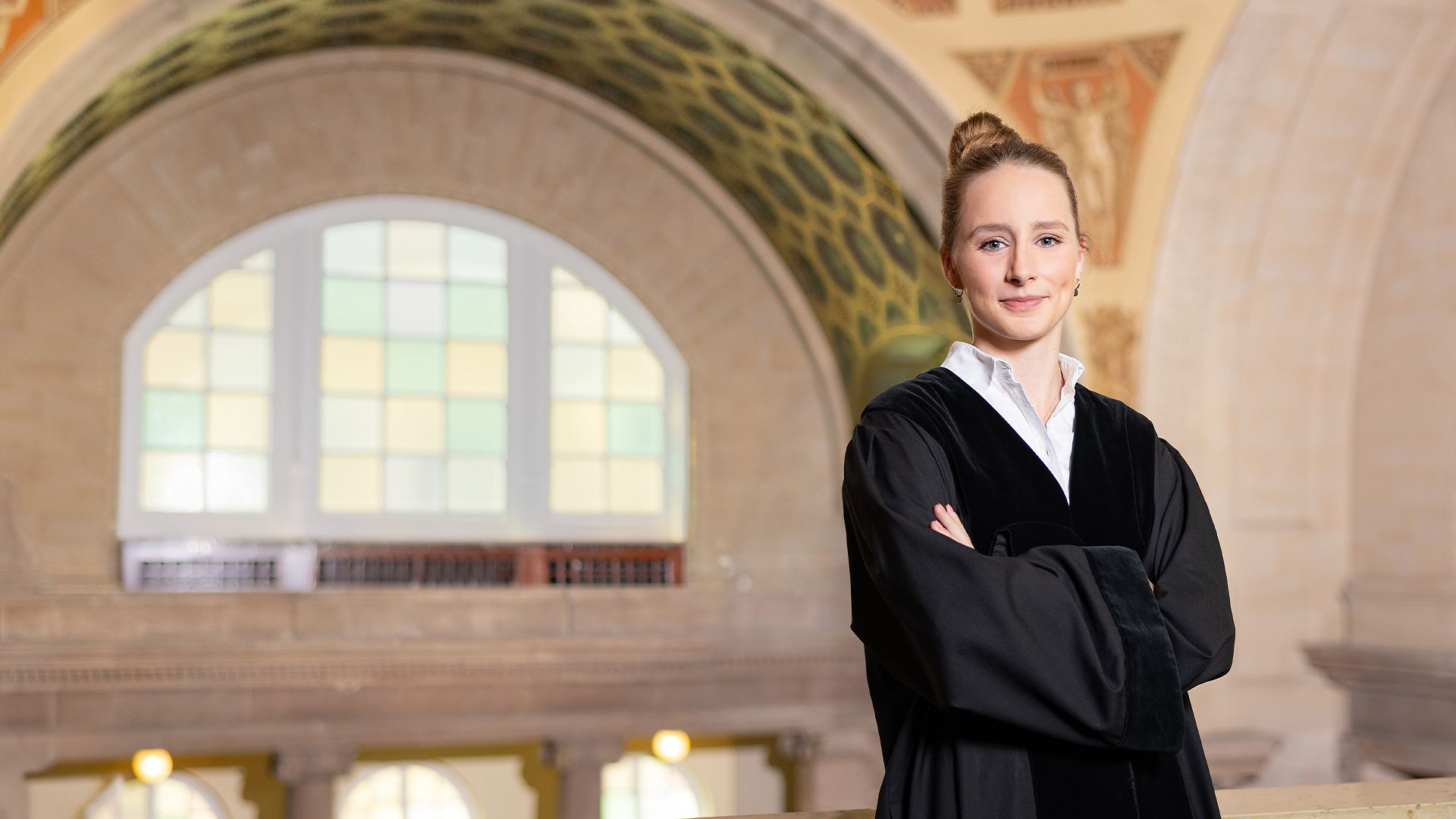 Eine Amtsanwältin in schwarzer Robe steht in einem Gerichtsgebäude.