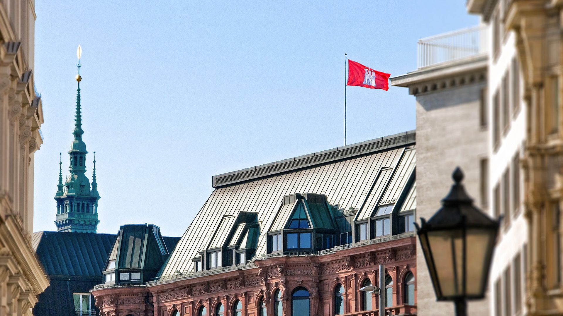 Es sind mehrere Hausdächer zu sehen und auf einem weht die Hamburger Flagge